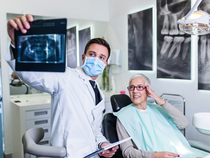 Stomatolog explicând planul de tratament unui pacient